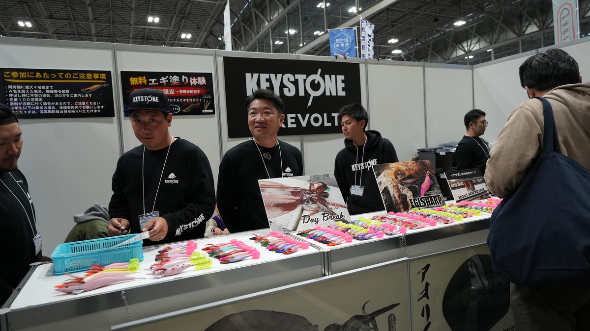 製品の説明をするキーストンスタッフ──カラフルなエギのラインナップが並ぶ
