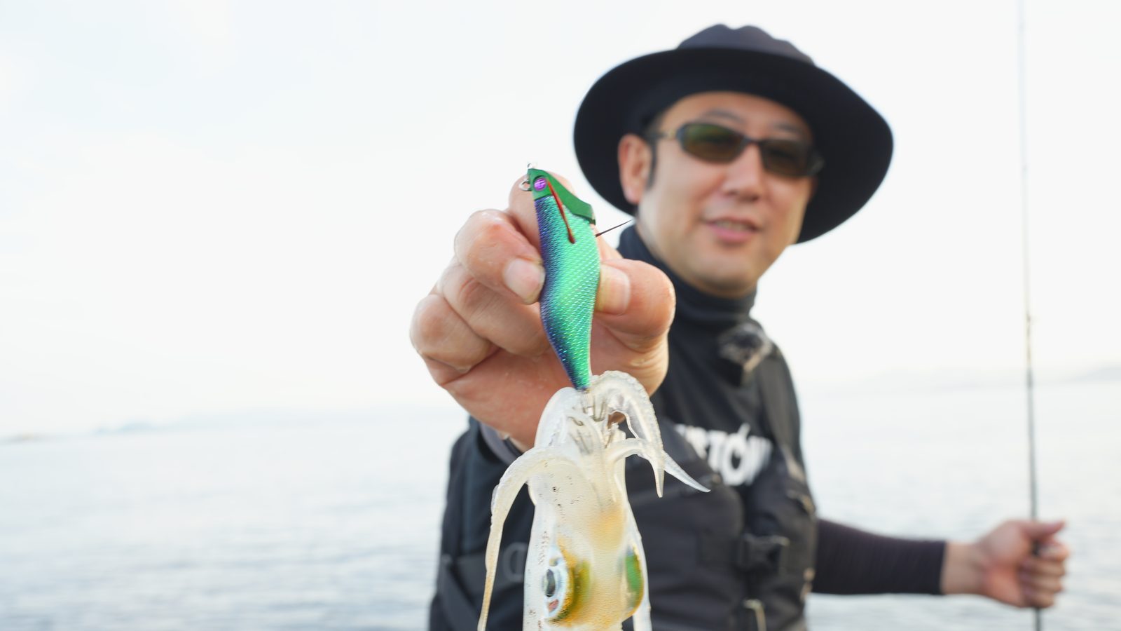 岸から釣り上げたアオリイカとジェットチェイサーを手にする釣り人